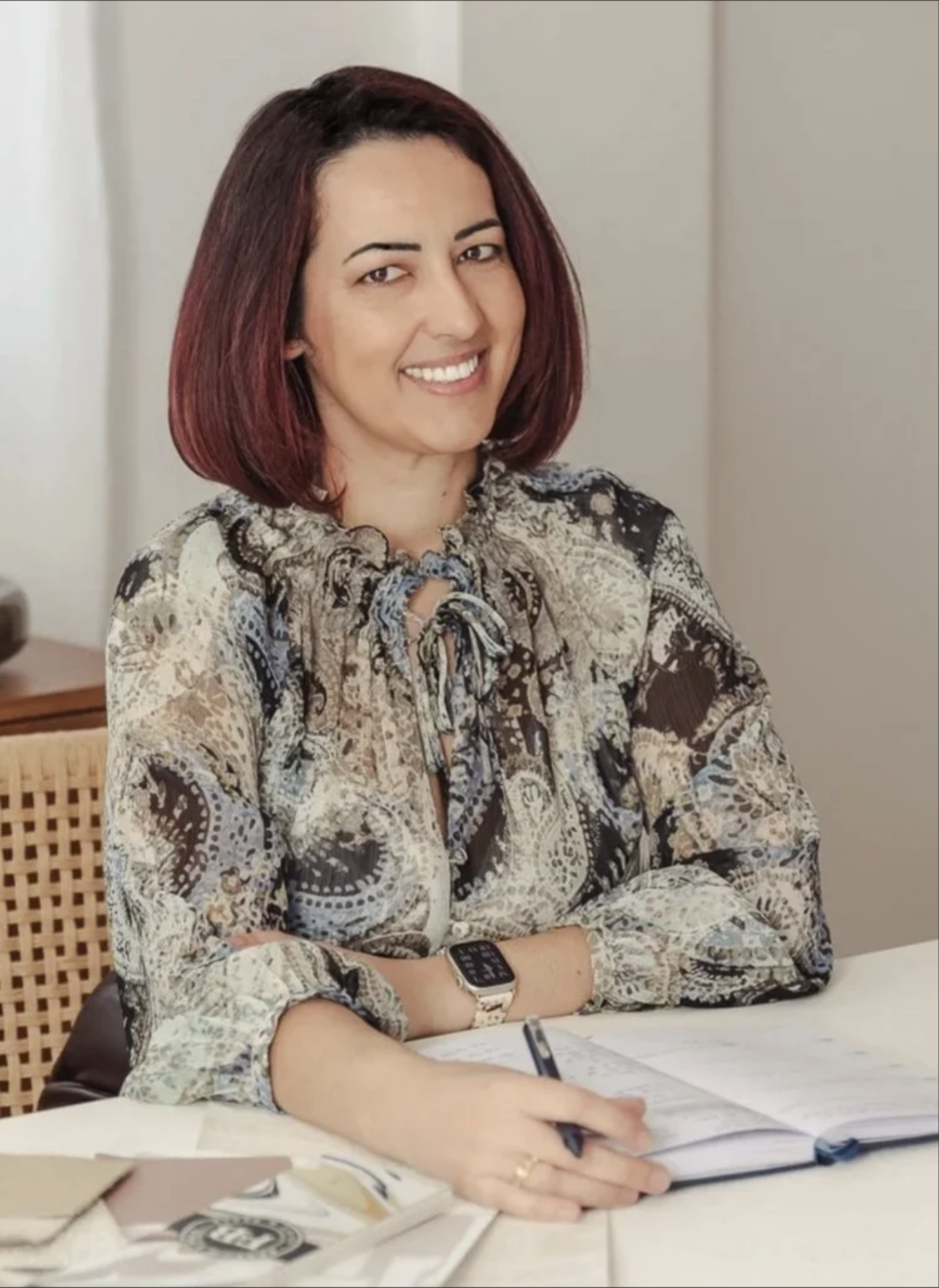 Marta Beccerril, an interior designer, smiling at her desk with an open notebook.
