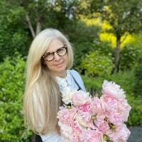 Pam holding a bouquet of pink flowers in a garden.