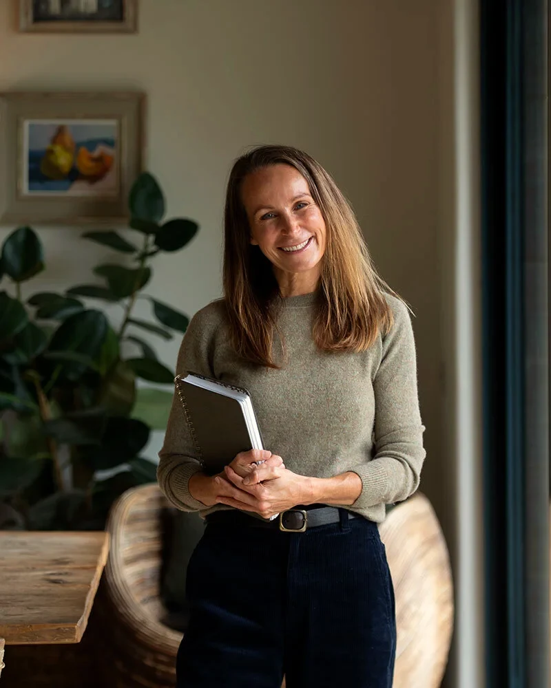 Philippa Craddock smiling in her studio, holding a notebook.
